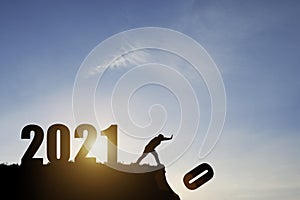 Man push number zero down the cliff where has the number 2021 with blue sky and sunrise. It is symbol of starting and welcome