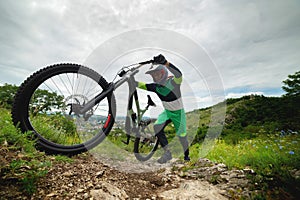 A man pushes a mountain bike up a hill. Adventure travel by bike. Guy athlete in defense lifts his equipment