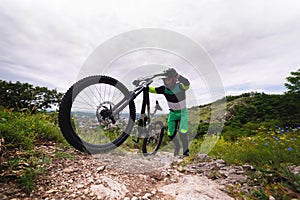man pushes a mountain bike up a mountain. Adventure travel by bike. Freestyle competition, mountain climb for downhill