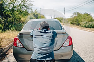 Man pushing a broken car breakdown on the road hot day. Car broken concept