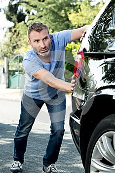 man pushing broken down car