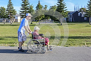 Man pushing elderly lady in wheelchair