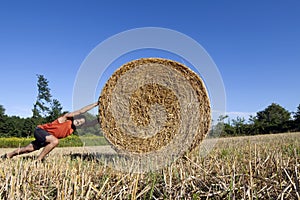 Man pushing hay bale