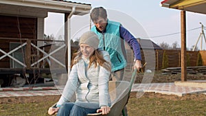 Man pushing his wife in a wheelbarrow