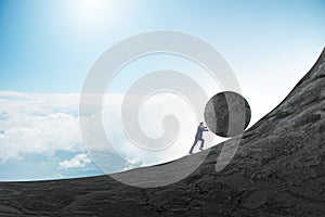 Man pushing large stone to the top photo