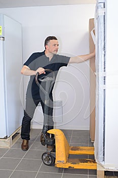 Man pushing pallet truck under fridge freezer