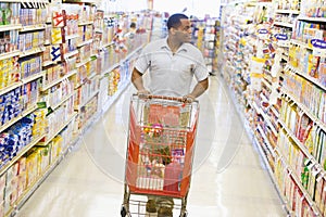 Man pushing trolley along supermarket aisle