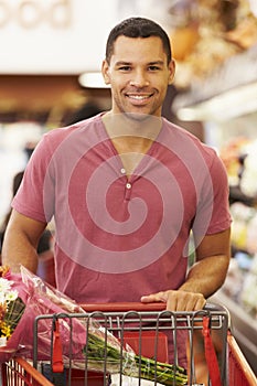 Man Pushing Trolley By Produce Counter In Supermarket