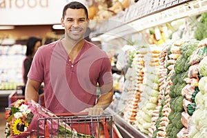 Man Pushing Trolley By Produce Counter In Supermarket