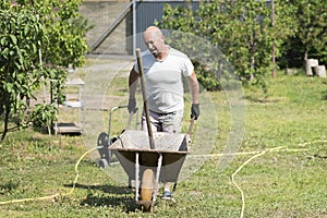 man pushing wheelbarrow. Young man pushing a wheelbarrow on the farm