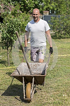 man pushing wheelbarrow. Young man pushing a wheelbarrow on the farm.