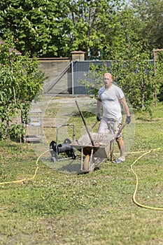 Man pushing wheelbarrow. Young man pushing a wheelbarrow on the farm