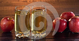 Man pust fresh healthy apple juice glass on wooden table. Two glasses with juice on the surface. Tasty juice in summer