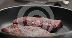 man put beef steak pieces on nonstick pan