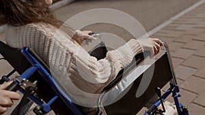 Man put his hand on hand of disabled woman on wheelchair, close up faceless shot. Concept ofparalysis, disability, help