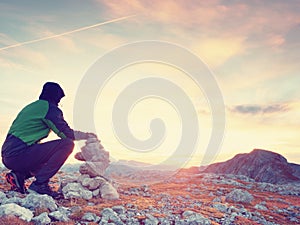 Man put the last stone intopeak of pyramid. Balanced stone pyramid on mountain summit.