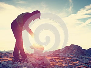 Man put the last stone intopeak of pyramid. Balanced stone pyramid on mountain summit.