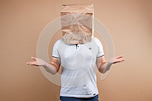 The man put a paper bag on his head, spreads his arms to the sides, despondency, depression. Isolate on yellow background, images