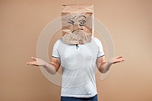 The man put a paper bag on his head, spreads his arms to the sides, despondency, depression. Isolate on yellow background, images