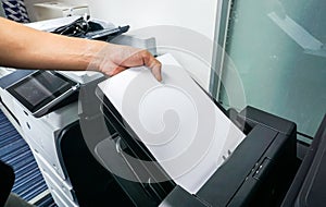 Man put paper sheet into office printer tray