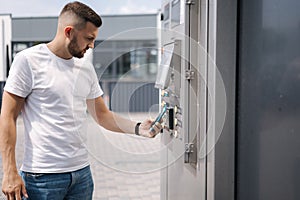 Man put plactic card for paying outdoors on self-service car wash