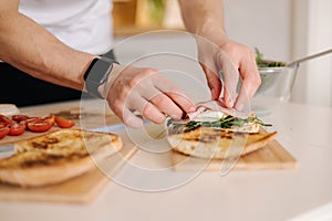 Man put slice of Italian prosciutto on top of bruschetta. Healthy home made food