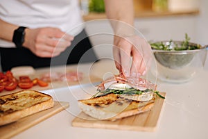 Man put slice of Italian salami on top of bruschetta. Healthy home made food