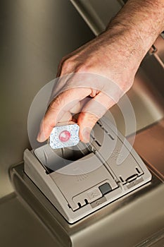 Man puting a tablet in the dishwashing machine