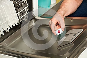 Man puting a tablet in the dishwashing machine