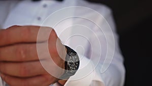 Man puts on an accessory - a stylish watch to see the time. Clock close-up