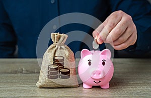 A man puts coins in a piggy bank. Accumulating money.