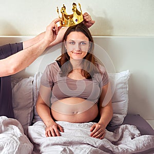 A man puts a crown on a pregnant woman. Husband and wife with a coronet on their head