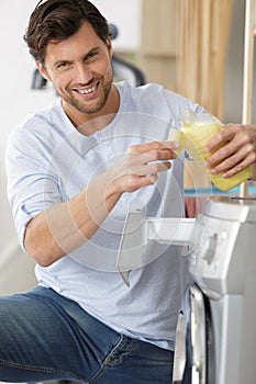 man puts detergent in washing machine