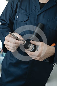 man puts a drill bit in an electric drill