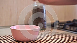 Man puts empty dog bowl on table and fills with healthy dry food