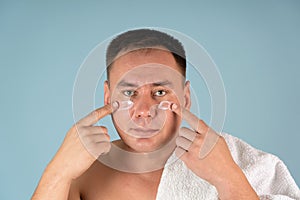 A man puts a face cream on his cheeks. Skin care