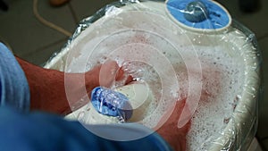 Man puts feet into footbath before pedicure. Metrosexual takes care of himself.