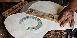 Man puts finishing touches on the inlay around a soundhole