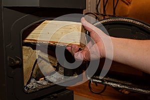 Man puts a firewood in a wood stove