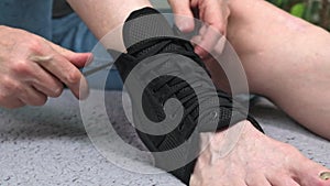 The man puts on a fixing bandage with lacing on the injured leg in the ankle joint area. tying her shoelaces. close-up.