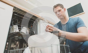 Man puts glass to the dishwasher