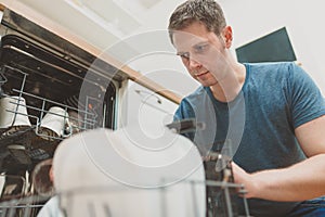 Man puts glass to the dishwasher