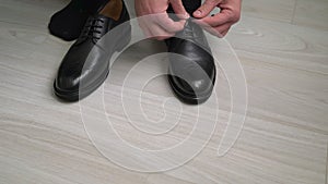 Man puts on his shoes. Male in a black suit and socks laces up his boots.