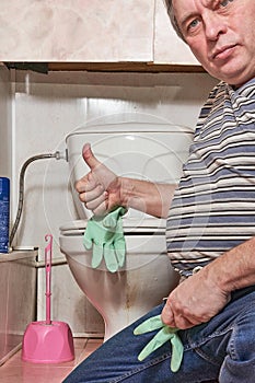 A man puts on household rubber gloves to wash a dirty toilet