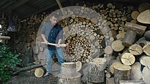 A man puts a log on a stump and chops it with an ax.