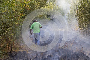 Man puts out a fire with an agricultural implement