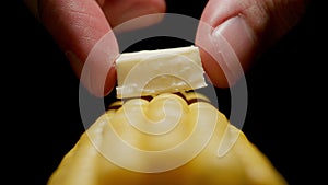 Man puts a piece of butter on sweetcorn cob. Close up.