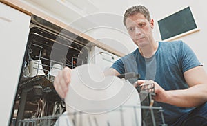 Man puts plate to the dishwasher