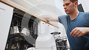 Man puts plate to the dishwasher.