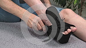 The man puts on special fixing bandage on the injured leg in the ankle. close-up